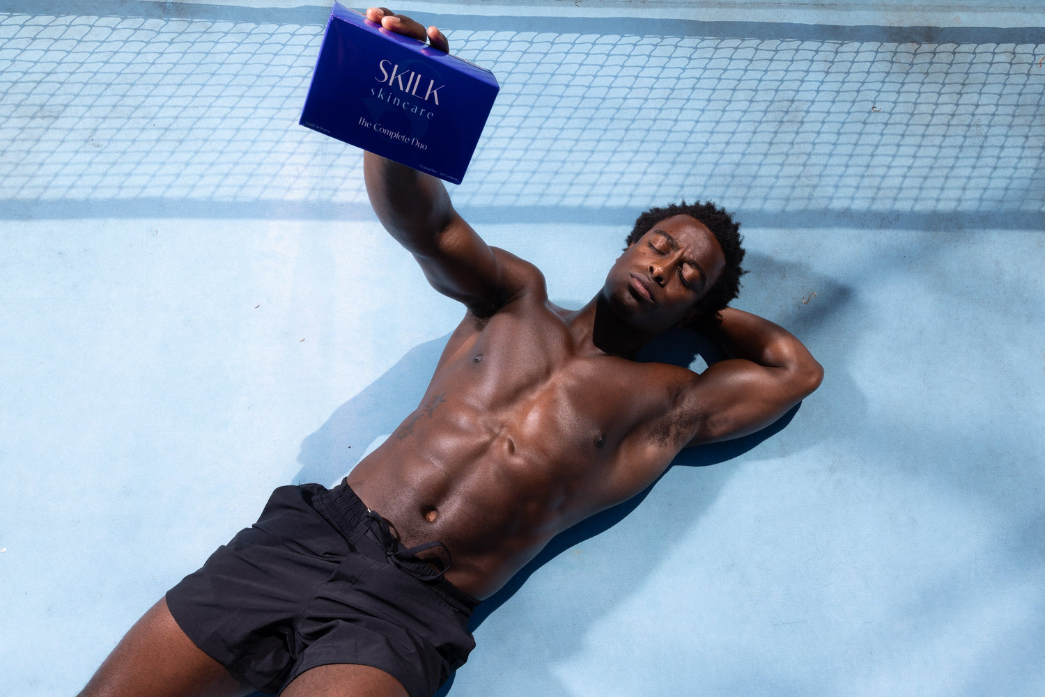 Man lying on pickle ball court holding Skilk Skin