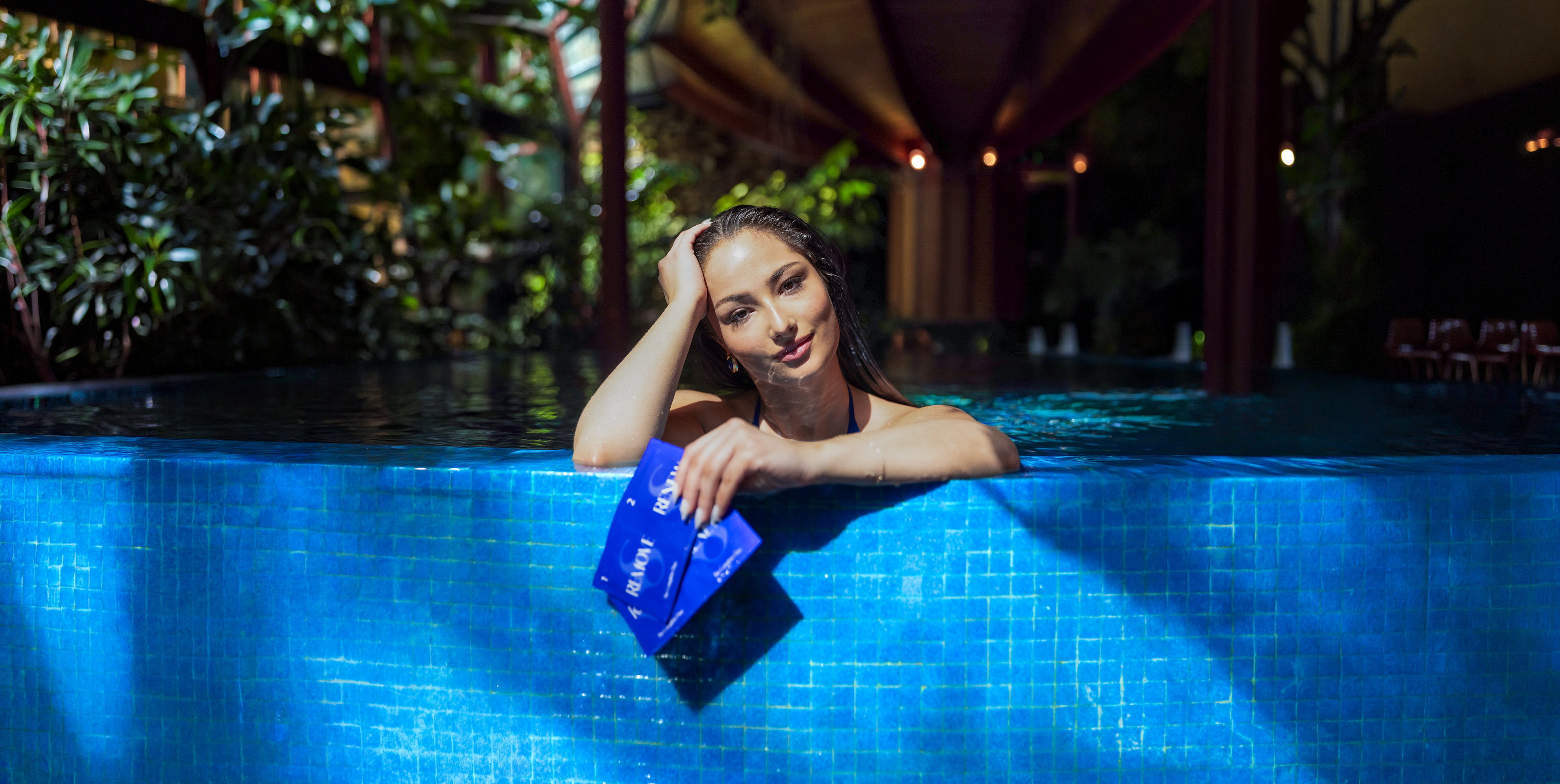 Woman, Blake Skilken in pool holding Skilk Skin The Complete Duo wipes over ledge of pool